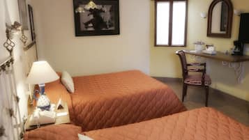Habitación con dos camas, un escritorio, una silla, una lámpara, un teléfono y un cuadro en la pared.