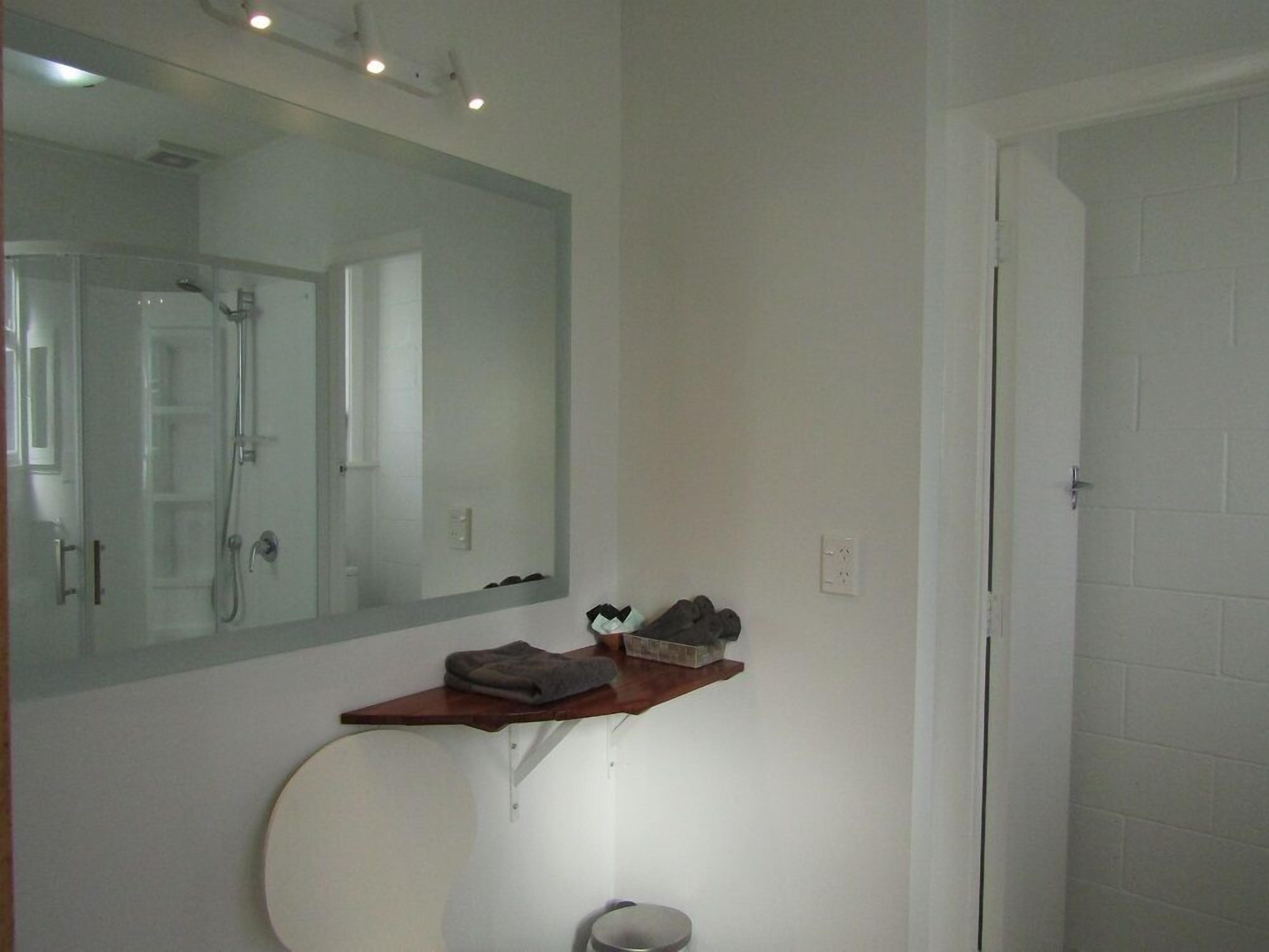 A bathroom with a large mirror, a shower, and a towel rack.