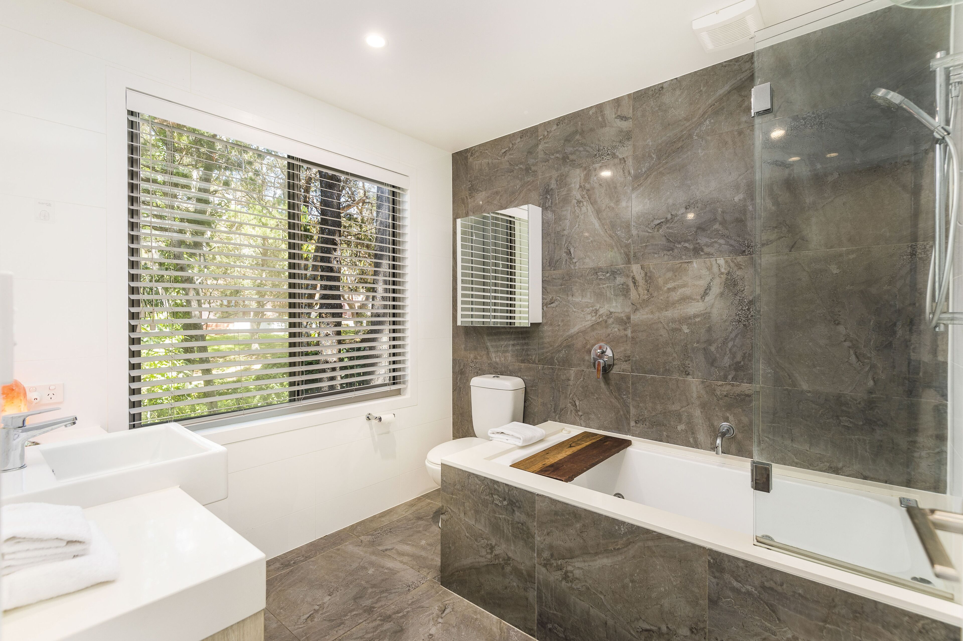 A modern bathroom with a large window, a bathtub, and a shower area.