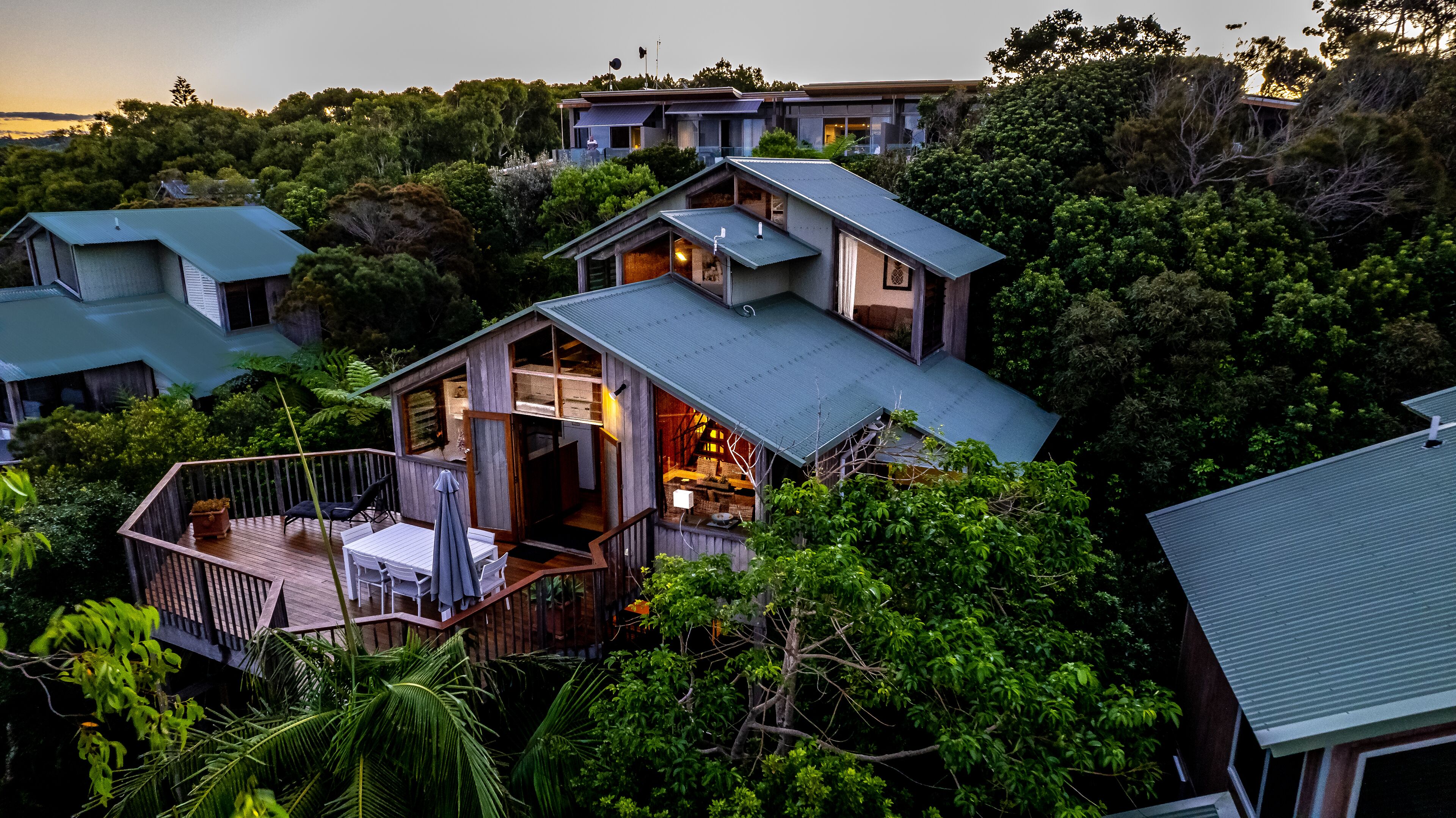 Une maison moderne dotée d’une terrasse, entourée d’une végétation luxuriante.