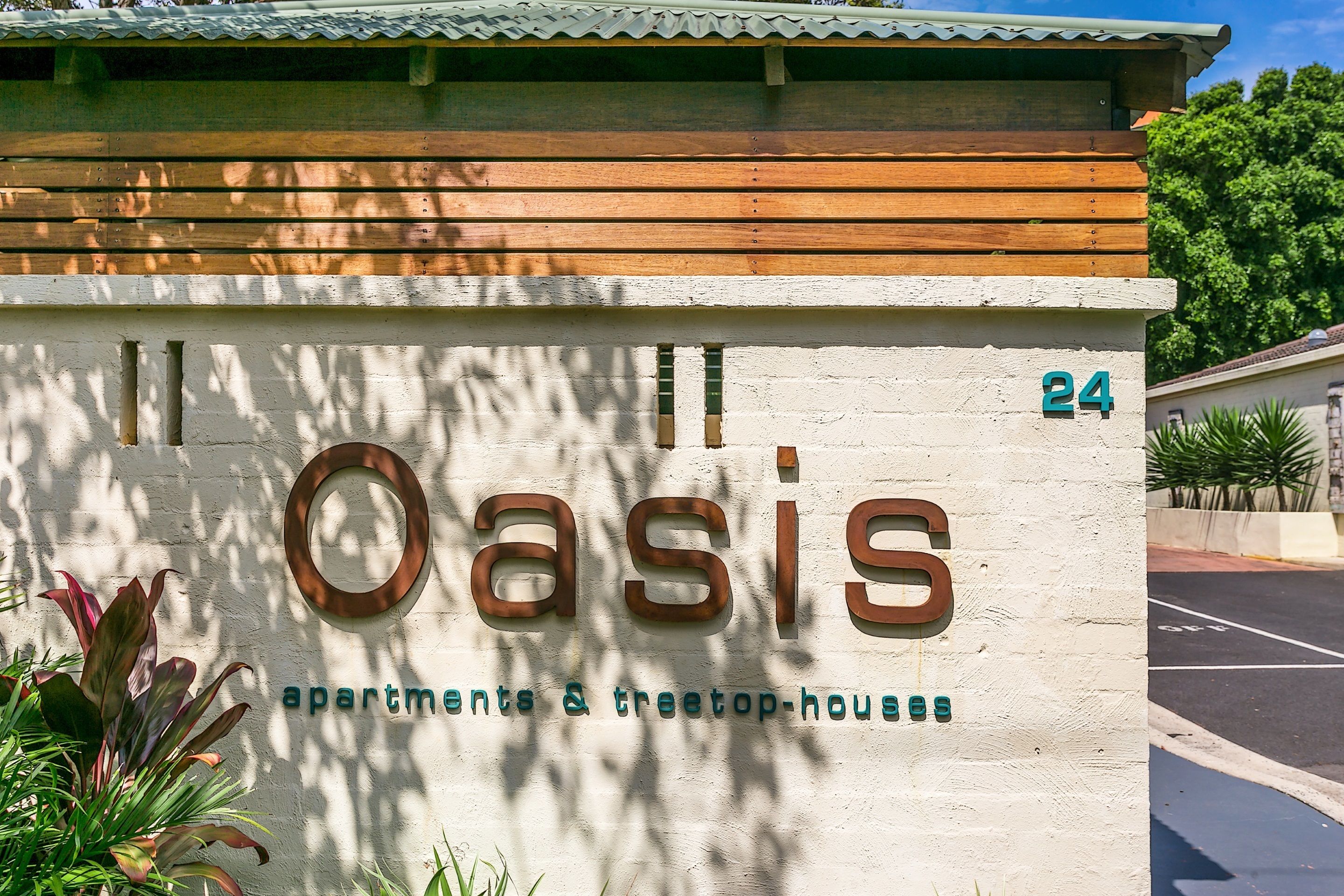 A building sign with the name "Oasis" and the text "apartments & treetop houses" indicating the type of accommodations available.
