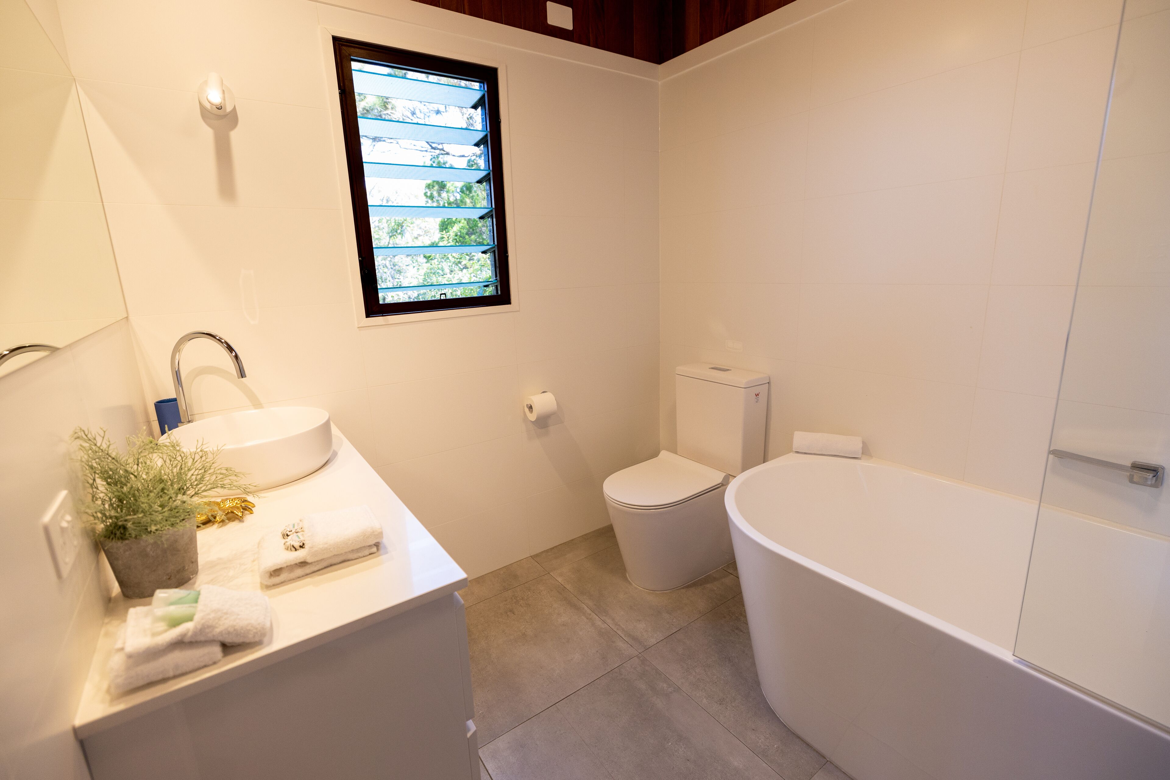 A modern bathroom with a sink, toilet, and bathtub.