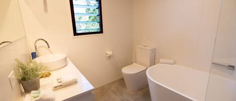 A modern bathroom with a sink, toilet, and bathtub.