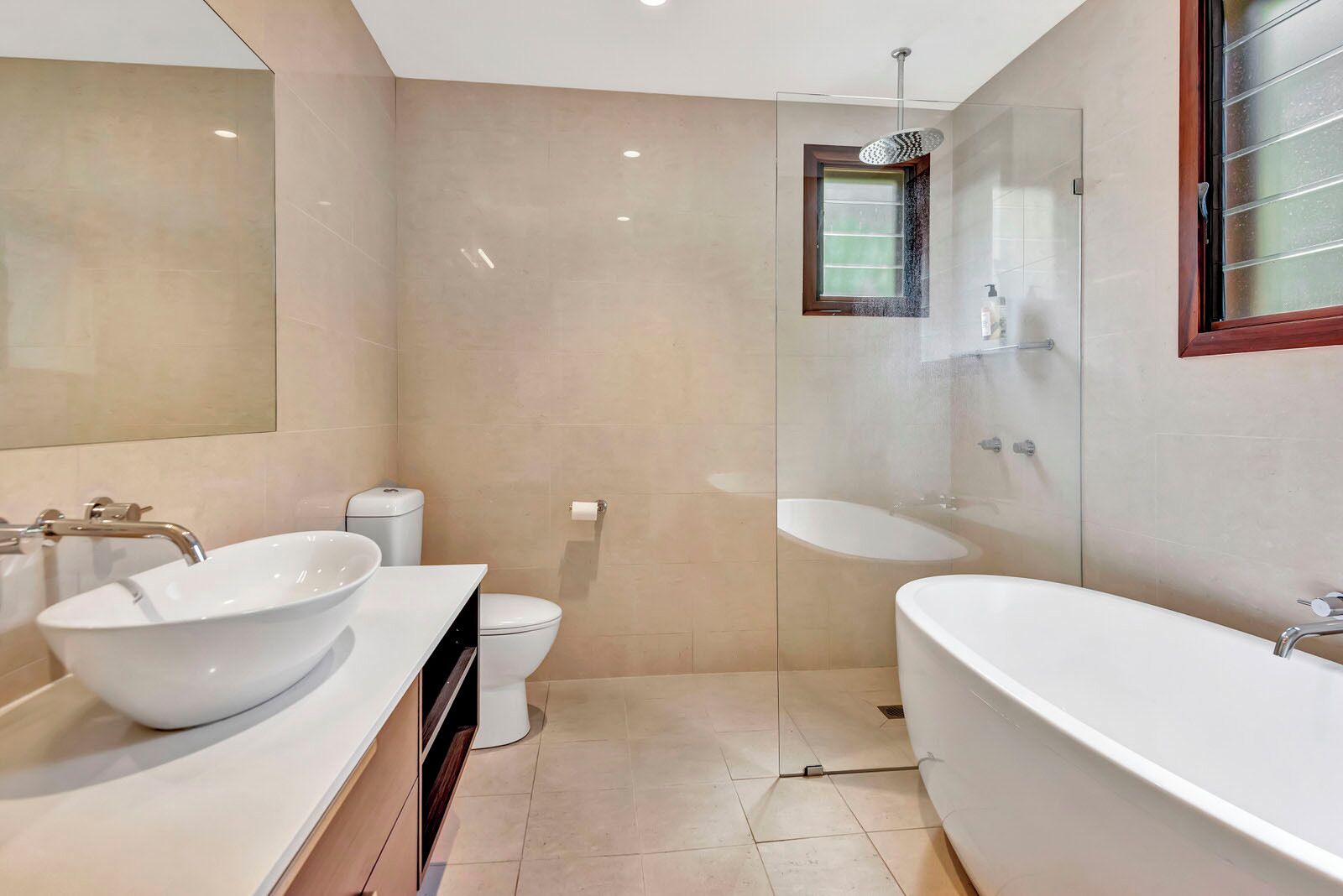 A modern bathroom with a large bathtub, a freestanding sink, and a glass-enclosed shower area.