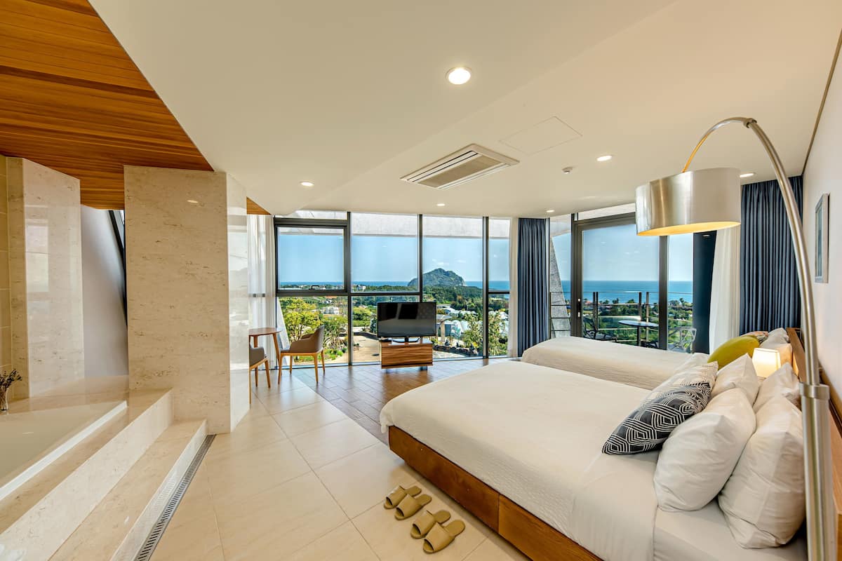 A modern bedroom with a large bed, a TV, and a view of the city.