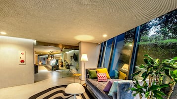 A modern interior with a sofa, patterned rug, and a potted plant.