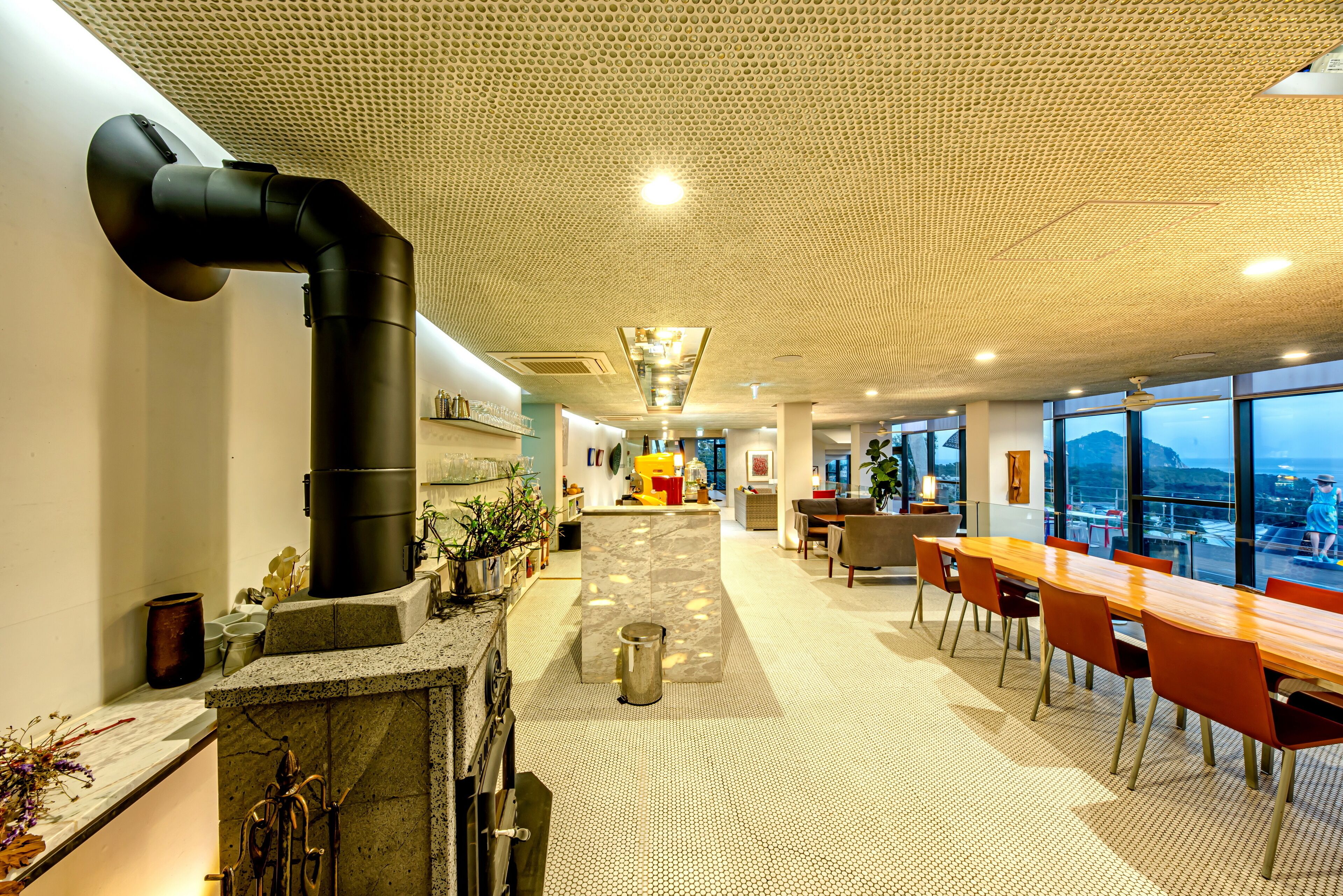 A modern interior with a central island, seating area, and large windows.