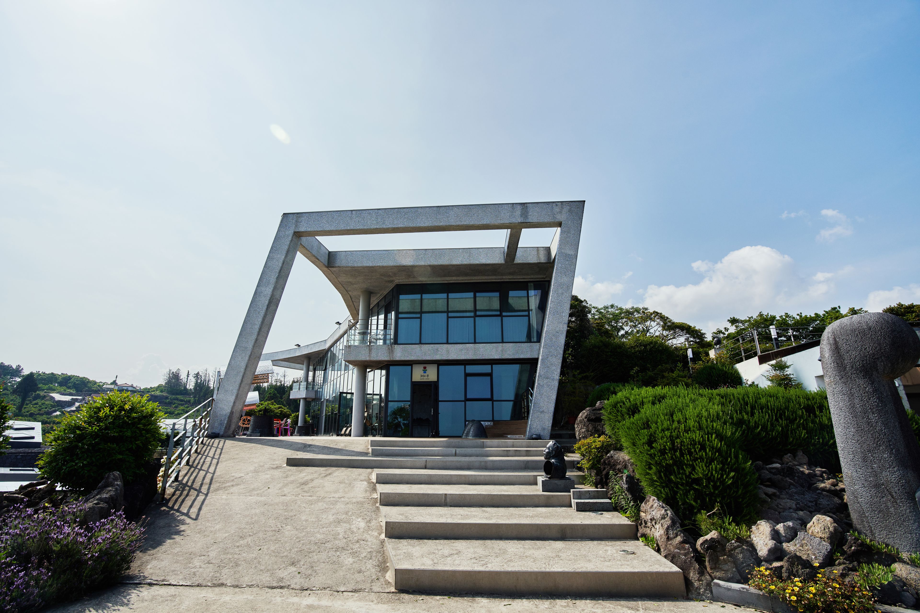 A modern building with a unique angular design, featuring a staircase leading to a glass entrance.