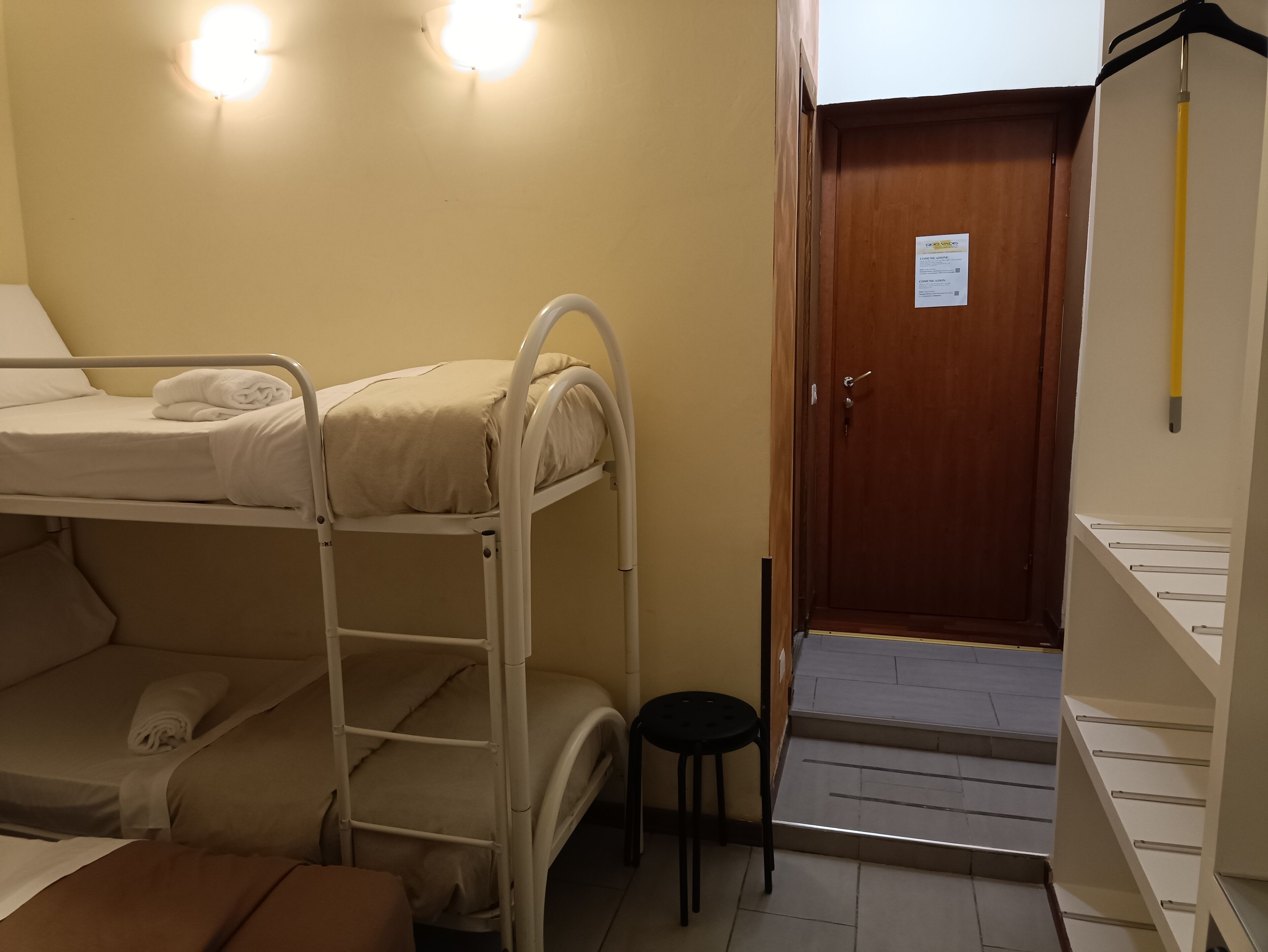 A bunk bed room with a wooden door and a small stool.