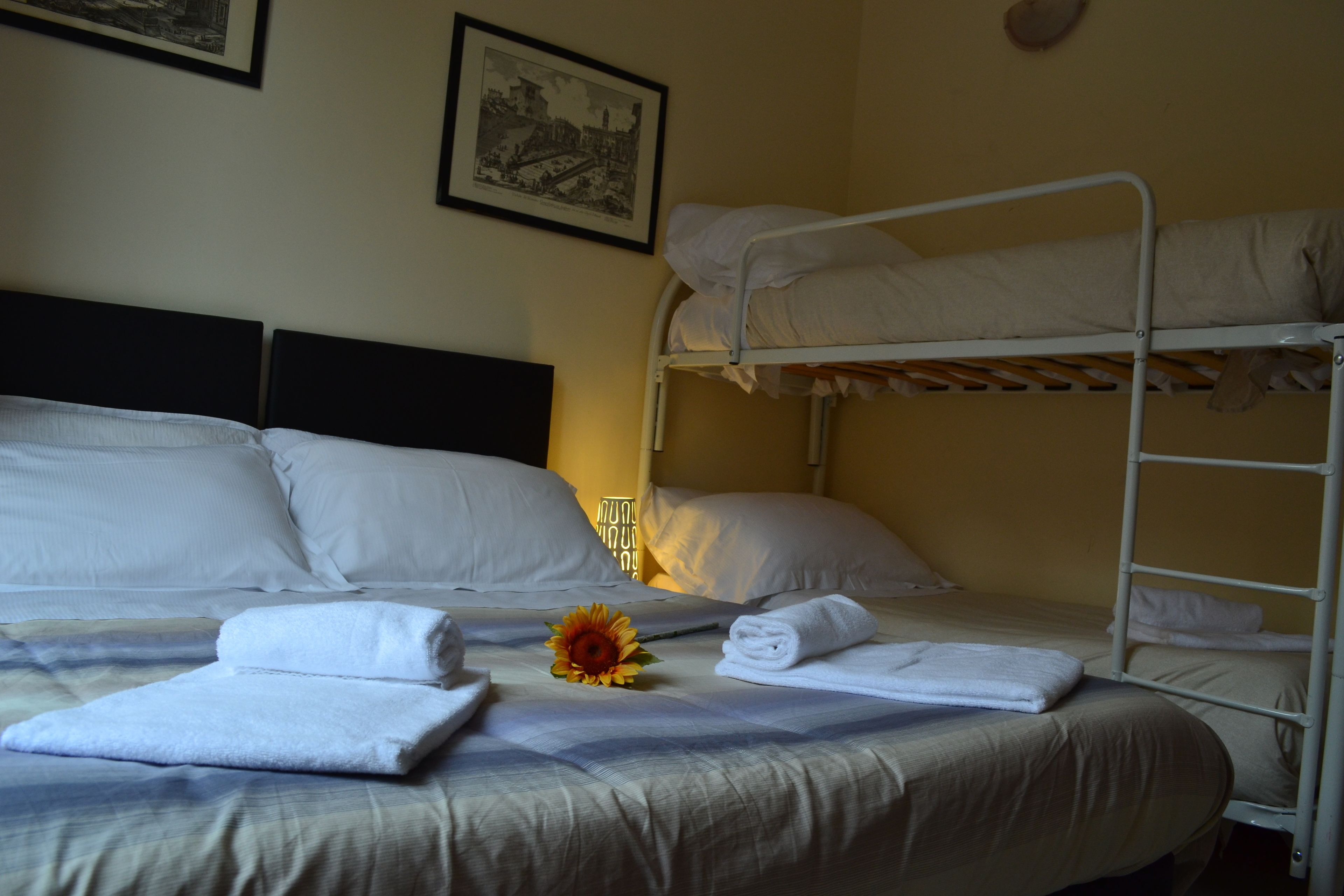Une chambre d’hôtel avec un lit superposé, un lit simple et un tableau accroché au mur.