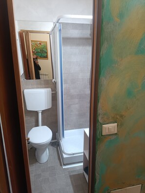 A bathroom with a toilet, a shower enclosure, and a tiled floor. - Enjoy Roma (Rome)