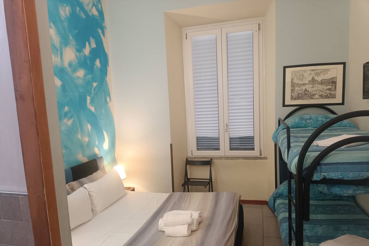 Quarto com cama, escrivaninha e janela.