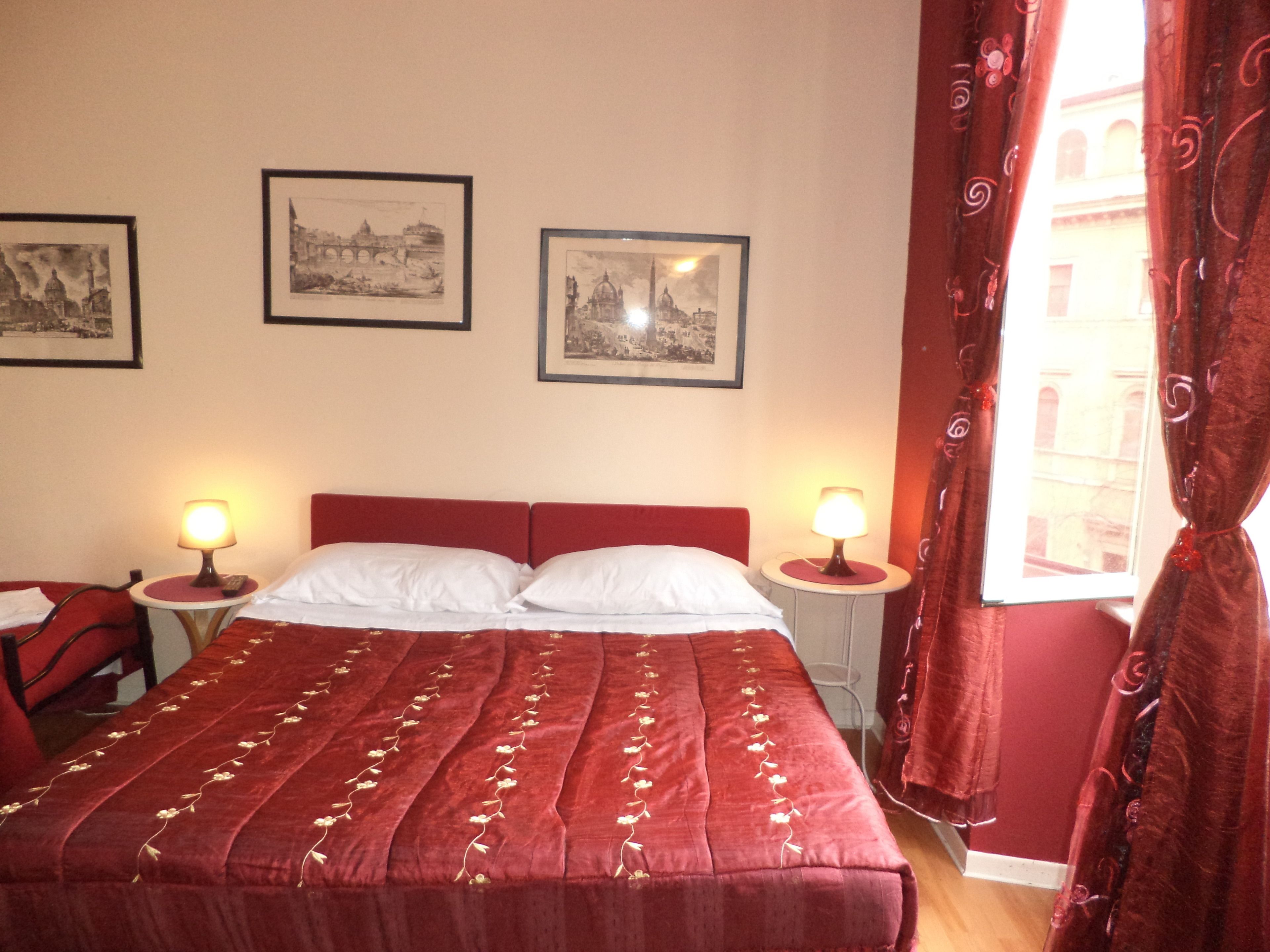 Une chambre d’hôtel avec un grand lit, deux tables de chevet avec des lampes et trois tableaux encadrés au mur.