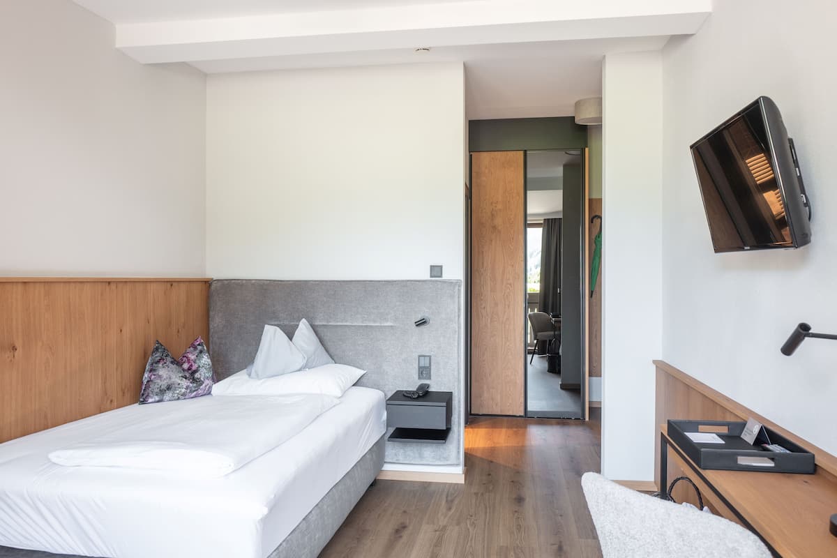 Een moderne hotelkamer met een groot bed, een nachtkastje, een flatscreen-televisie aan de muur en een houten hoofdbord.