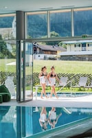 Una piscina cubierta, una piscina al aire libre, sombrillas, tumbonas