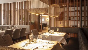 Ein Restaurantinneres mit Holzwandverkleidung, runden Pendelleuchten und ordentlich gedeckten Tischen.