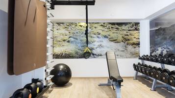 Ein Fitnessraum mit Trainingsgeräten, einer Klimmzugstange und einer großen Wandmalerei.