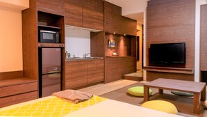 A modern hotel room with a bed, a TV, a microwave, a refrigerator, and a small kitchenette. - Hotel Sunset Hill (Onna)