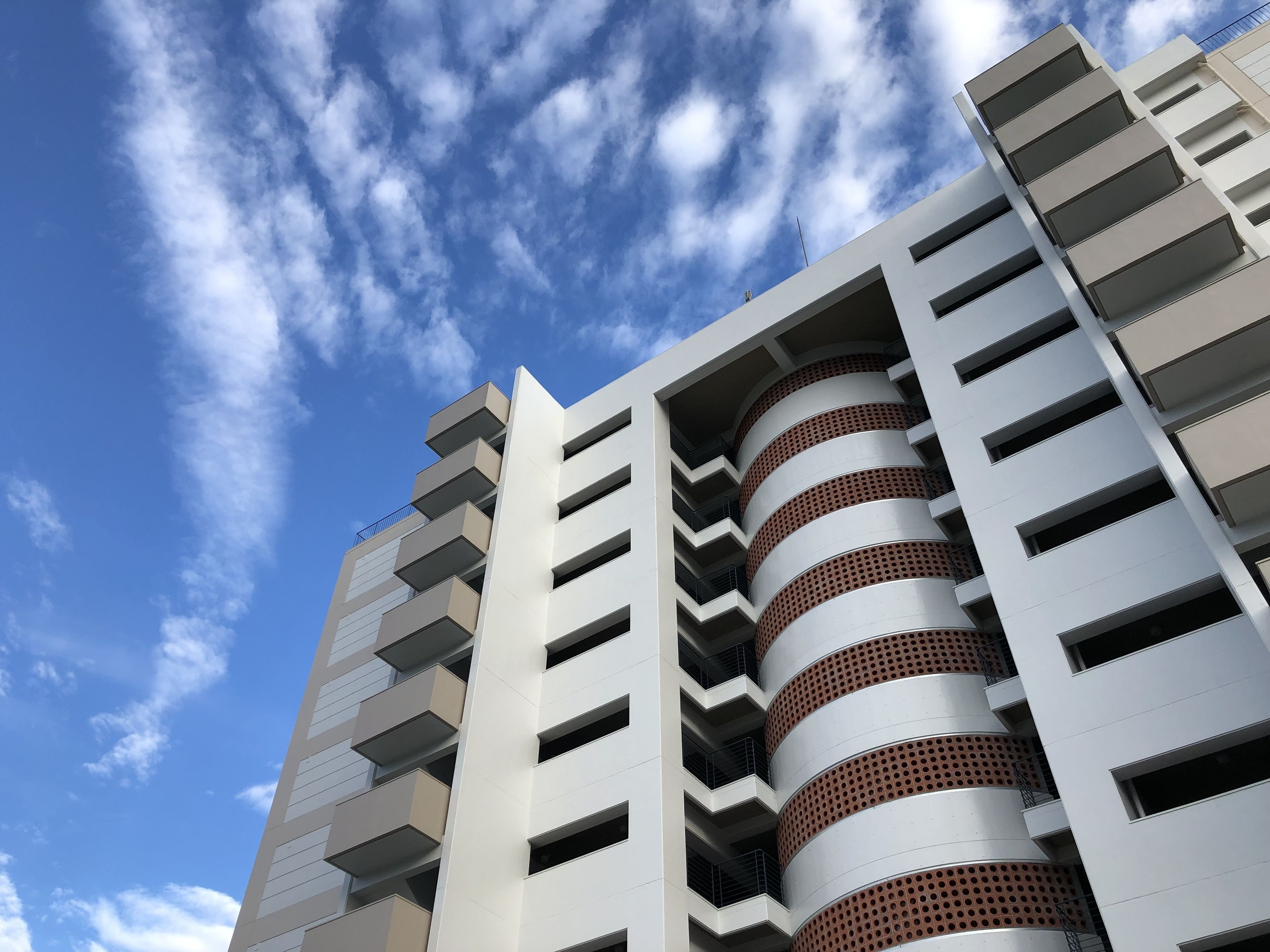Un moderno edificio de gran altura con varios balcones y un cielo despejado.