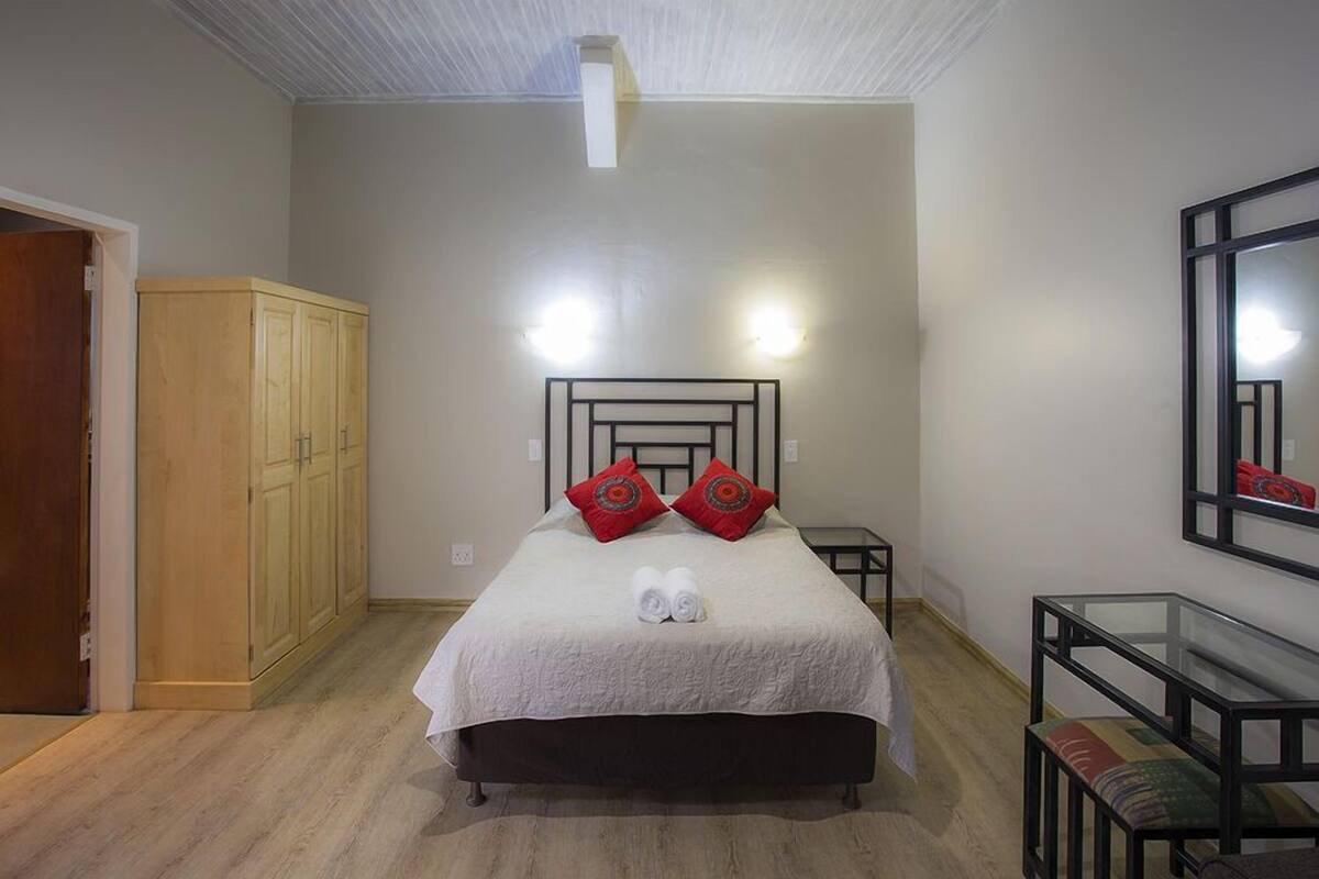 A bedroom with a bed, two bedside tables, a wardrobe, and a mirror on the wall.