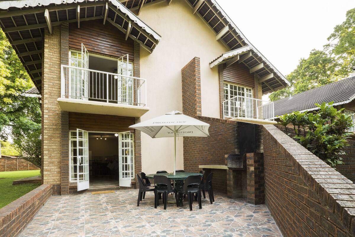 A patio with a table and chairs, an umbrella, and a brick wall.