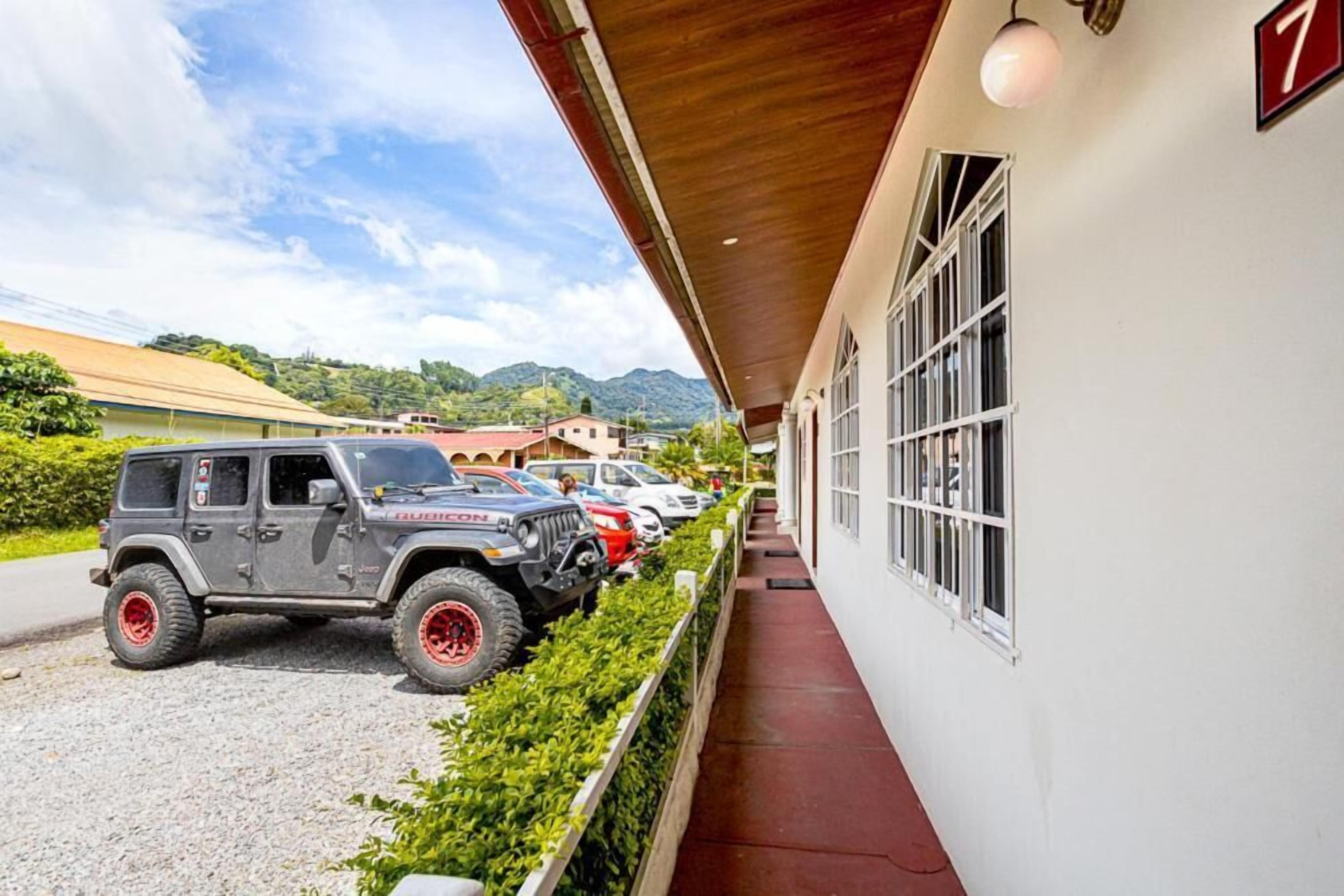 A covered outdoor area with a row of parked vehicles, including a Jeep, and a building with a number '7' sign.