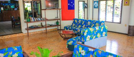 A spacious room with a large flag, a television on a stand, and a seating area with floral upholstery.