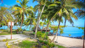 A beachside resort with palm trees, a thatched-roof hut, and a clear view of the ocean. - Va-i-moana Seaside Lodge (Asau)