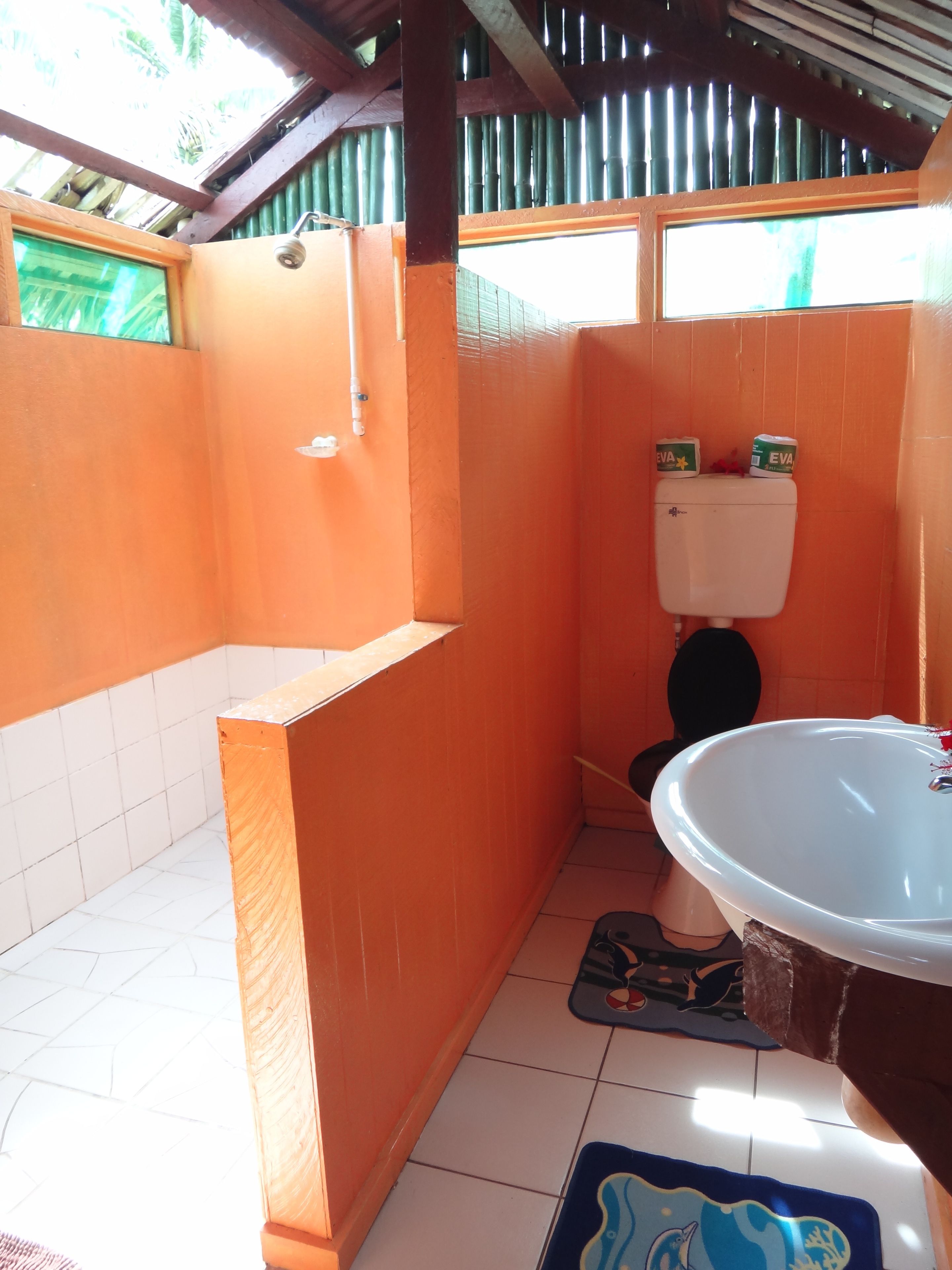 Ein Badezimmer mit orangefarbenen Wänden, einem weißen Waschbecken und einer Toilette.