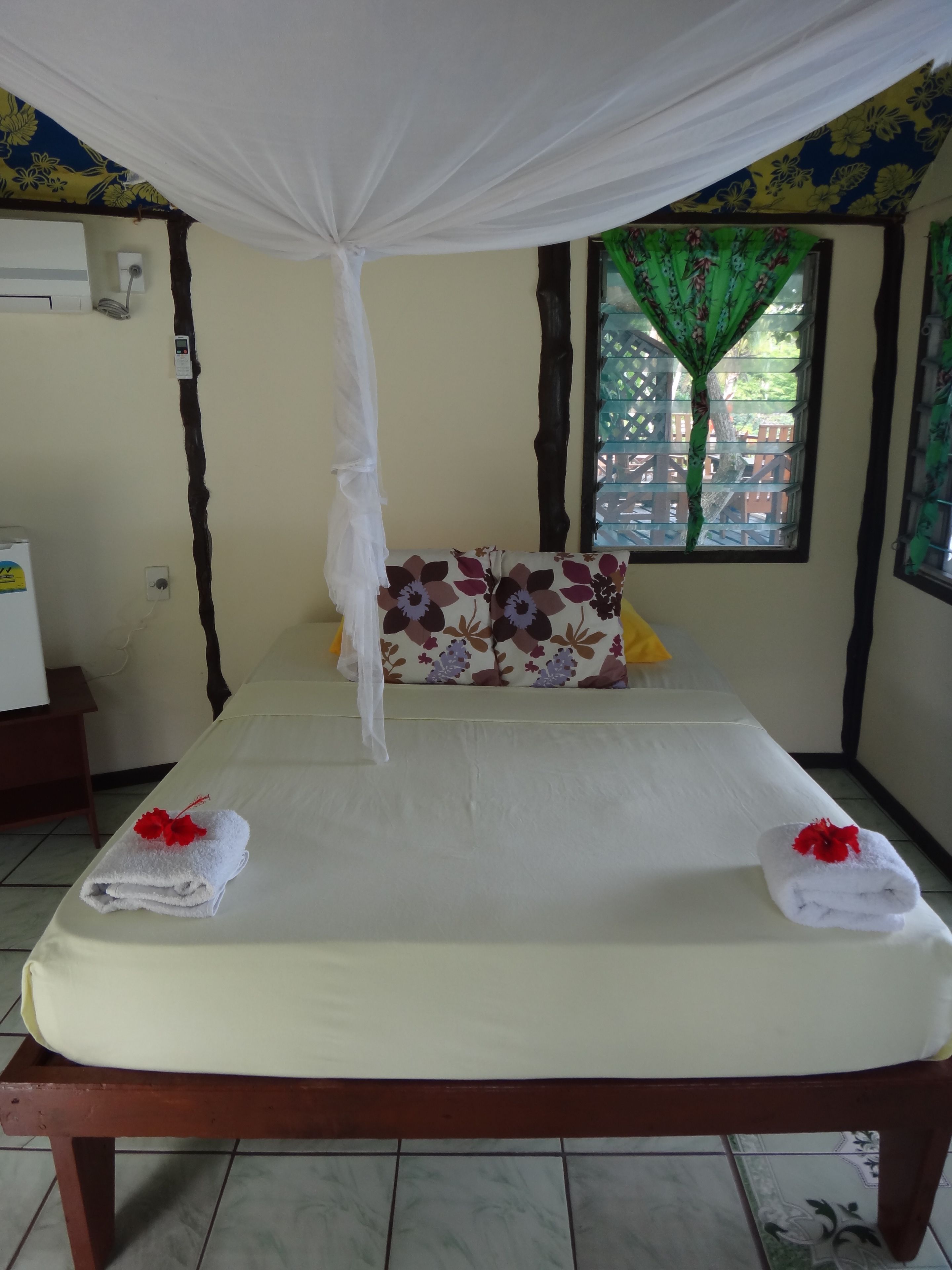 A bed with a canopy, floral pillows, and towels with flowers.