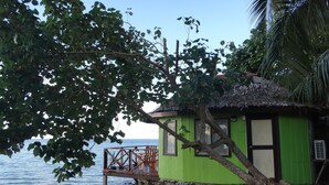 A green building with a wooden deck overlooking the sea. - Va-i-moana Seaside Lodge (Asau)