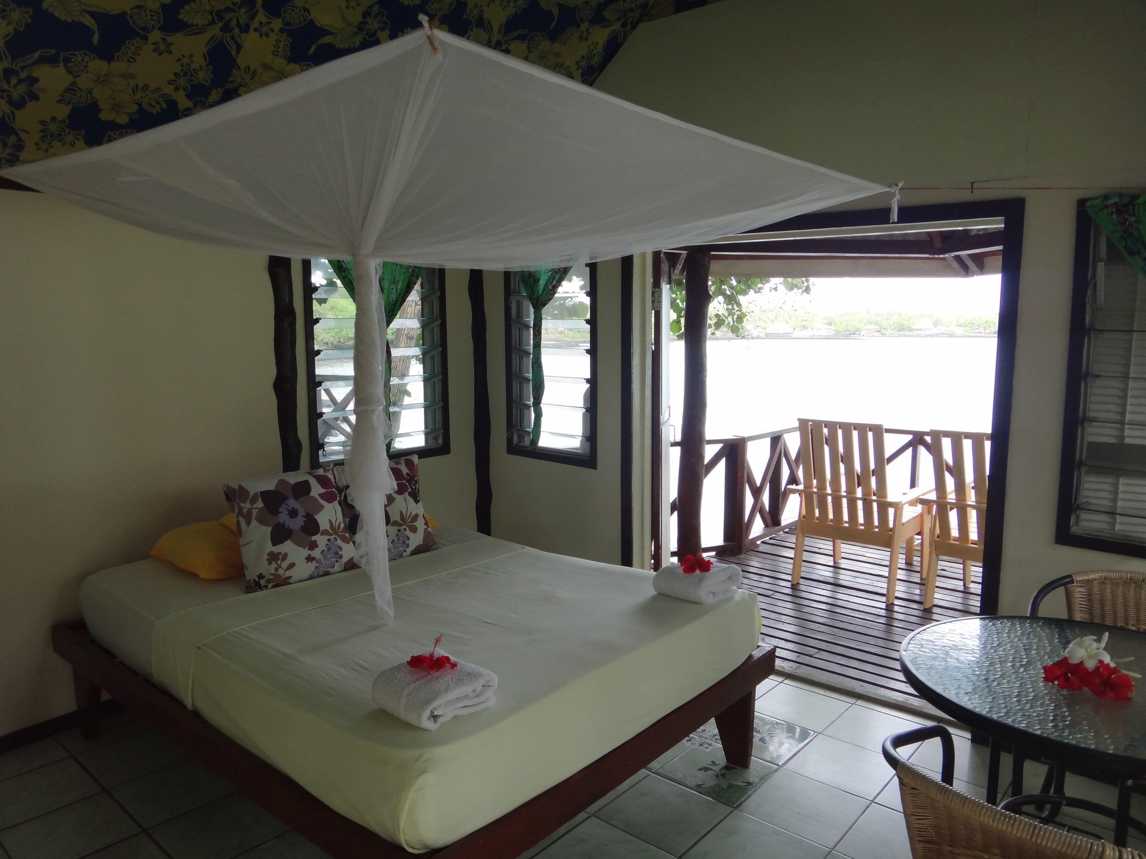 A bed with a canopy, a table with chairs, and a view of the outside.