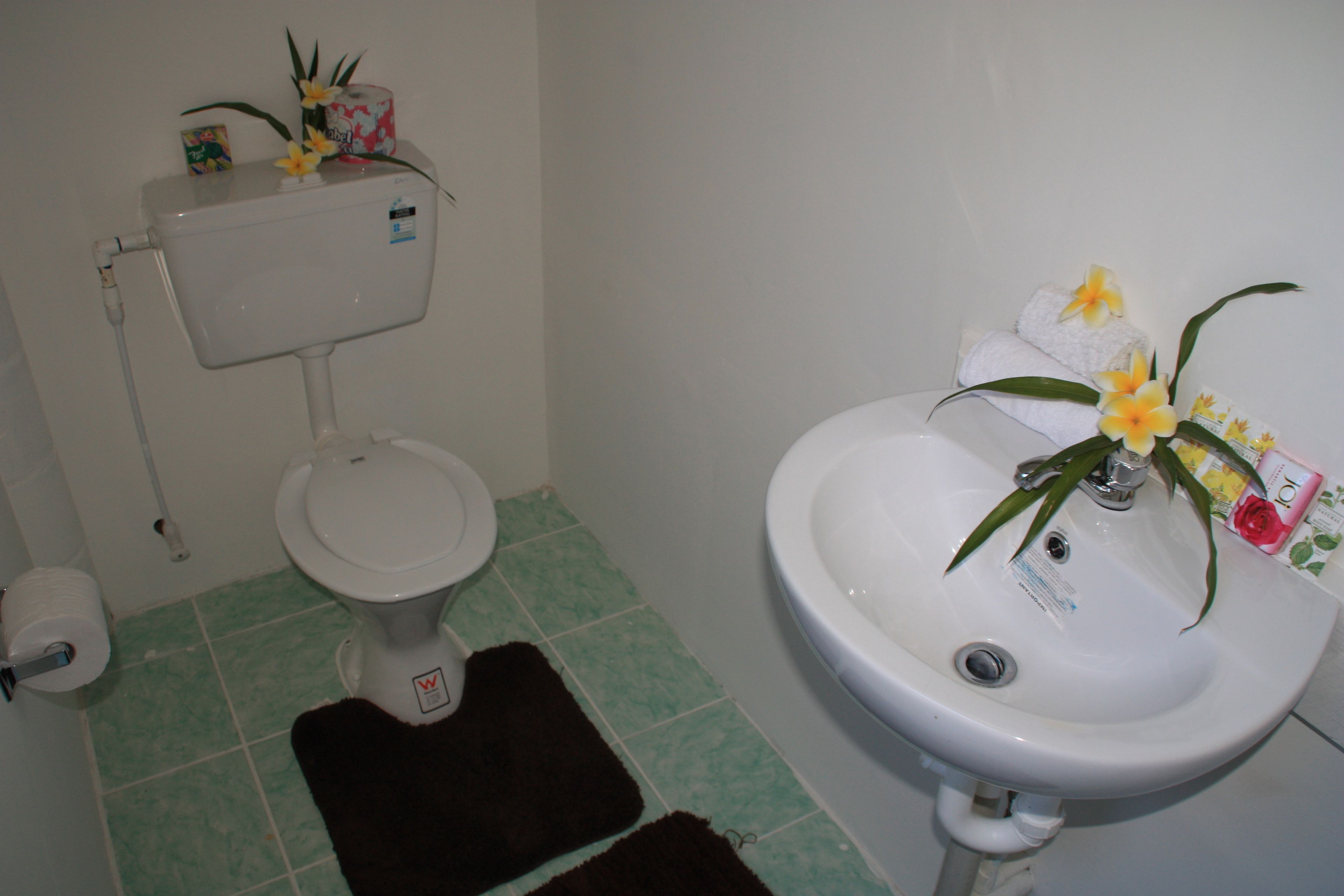 A bathroom with a toilet, sink, and green-tiled floor.