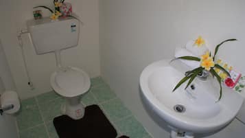 A bathroom with a toilet, sink, and green-tiled floor.