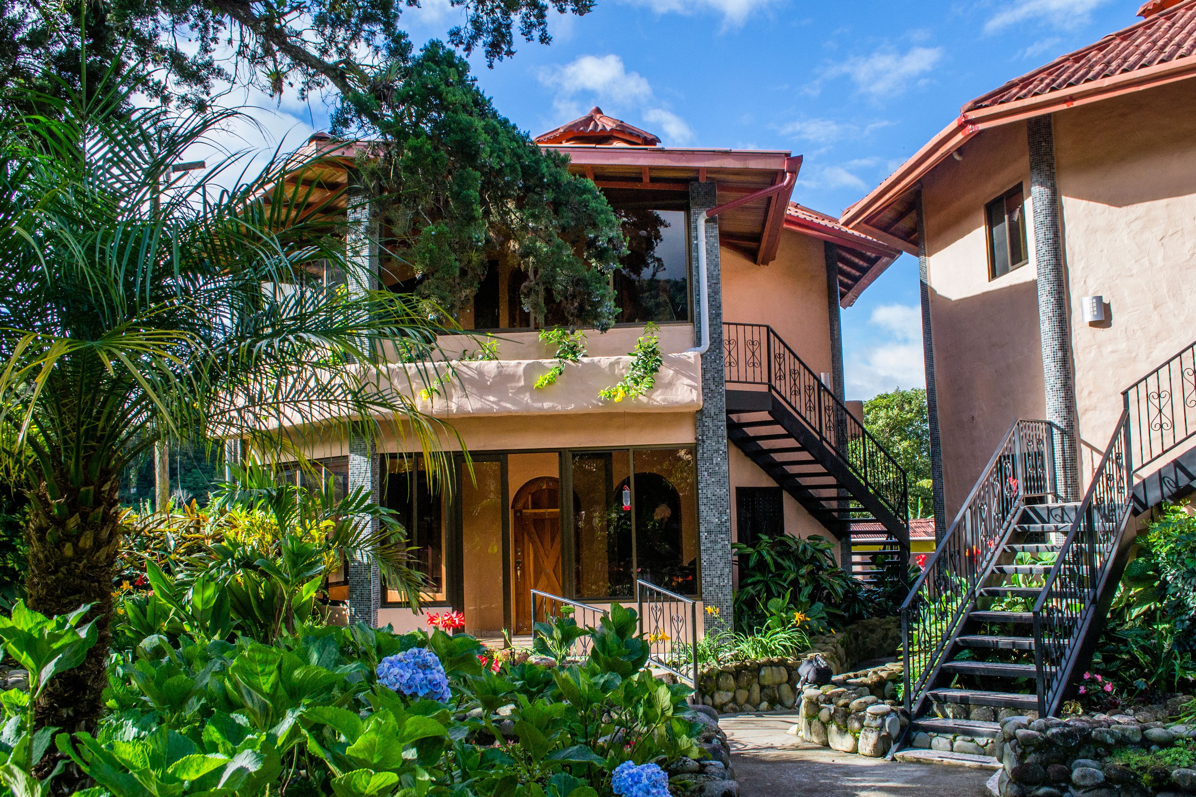 A two-story building with a red-tiled roof, a balcony, and a staircase.