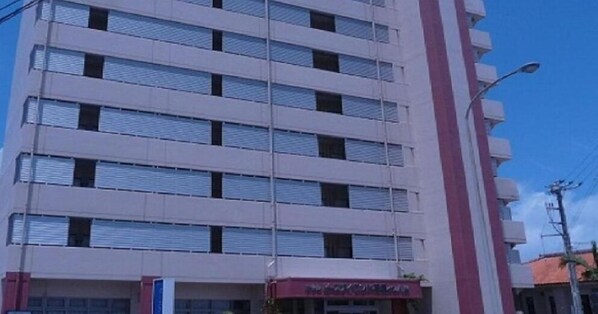 A multi-story building with a flat facade, large windows, and a red awning.
