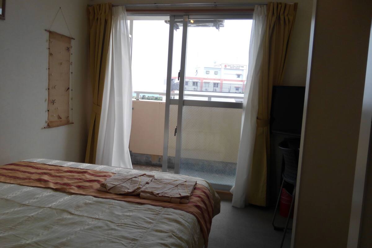 Une chambre d’hôtel avec un lit, un rideau, une porte coulissante et une vue sur l’extérieur.