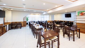 A spacious dining area with multiple tables and chairs, a reception desk, and a television mounted on the wall. - Hotel Peace Island Miyakojima (Miyakojima)