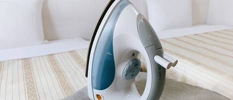 A modern, compact iron with a blue and white color scheme, placed on a grey surface in a room with a striped carpet and white furniture.