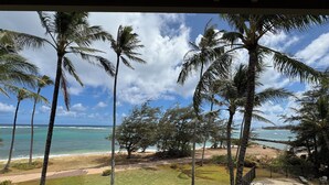 A pool area with a view of the ocean, surrounded by palm trees and a grassy lawn. - Hotel Coral Reef (Kapaa)