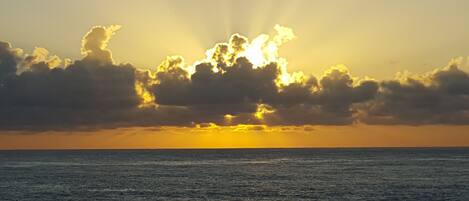 A sunset over the ocean with clouds and sunlight.