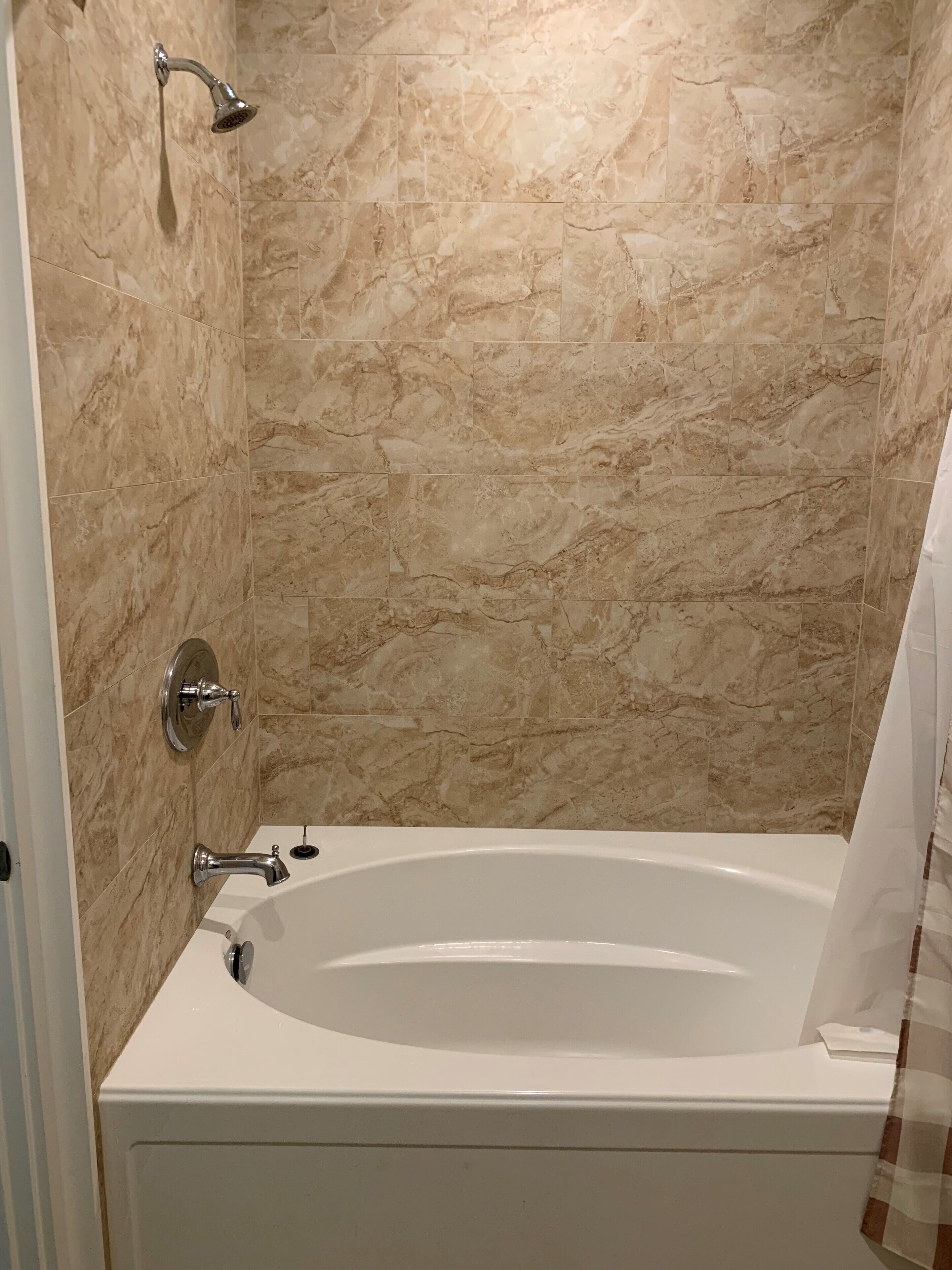 A bathroom with a bathtub, a showerhead, and a toilet.