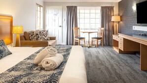 A hotel room with a large bed, a desk, a chair, a TV, and a window with curtains. - Country Motel Ipswich (Raceview)