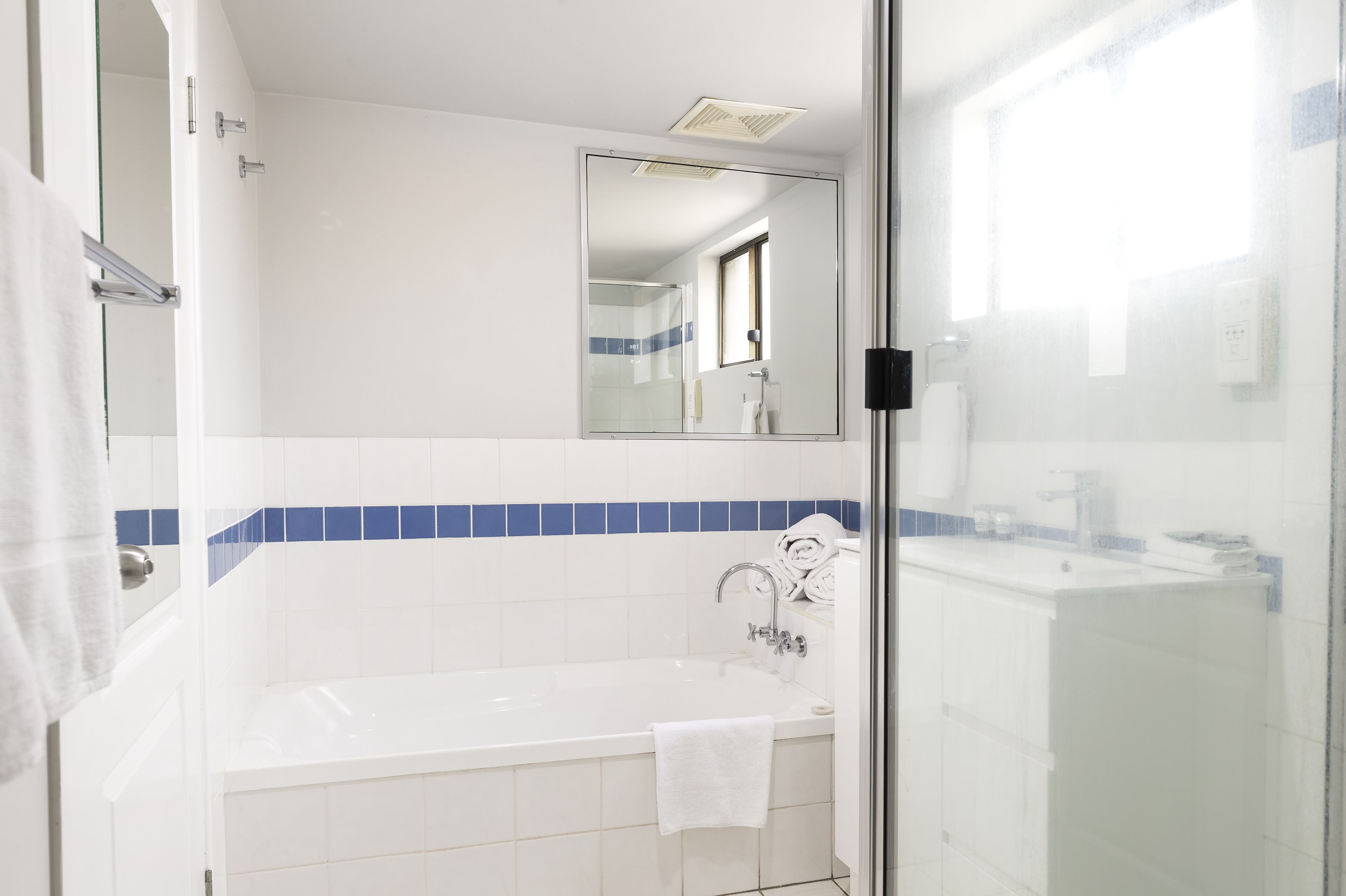 Une salle de bain moderne avec une douche à parois de verre, une baignoire blanche et un miroir au-dessus du lavabo.