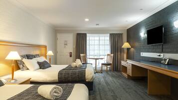 A hotel room with two beds, a desk, a chair, a TV, and a window with curtains.