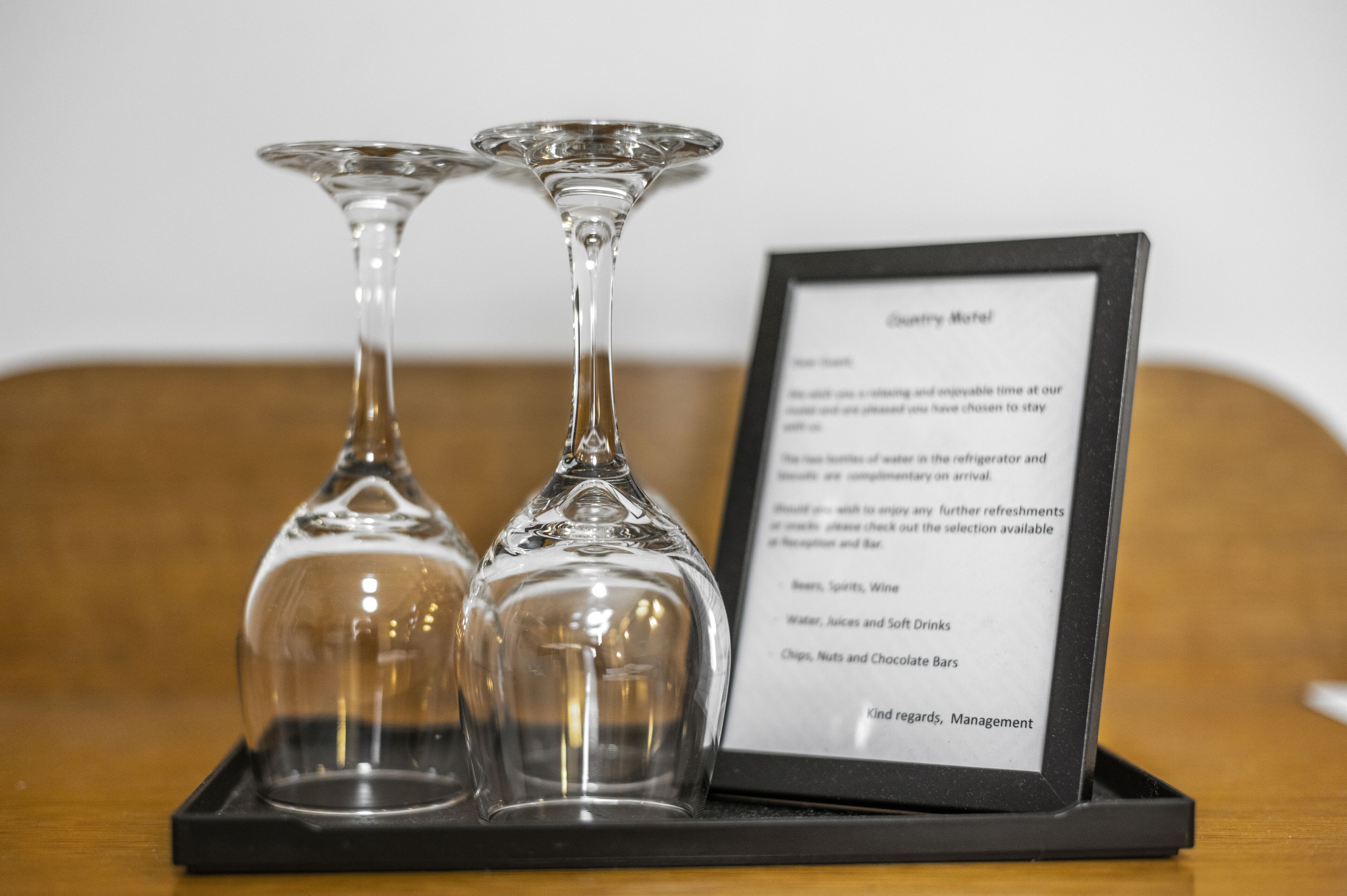 A menu board with a list of beverages and a tray with two empty wine glasses.
