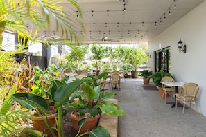 An outdoor patio area with tables and chairs, surrounded by potted plants and trees. - Country Motel Ipswich (Raceview)