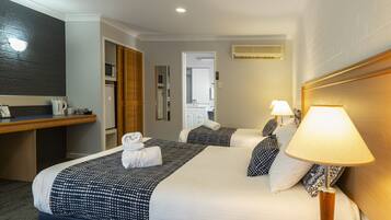 Habitación de hotel con dos camas, un escritorio, un microondas y un espejo.