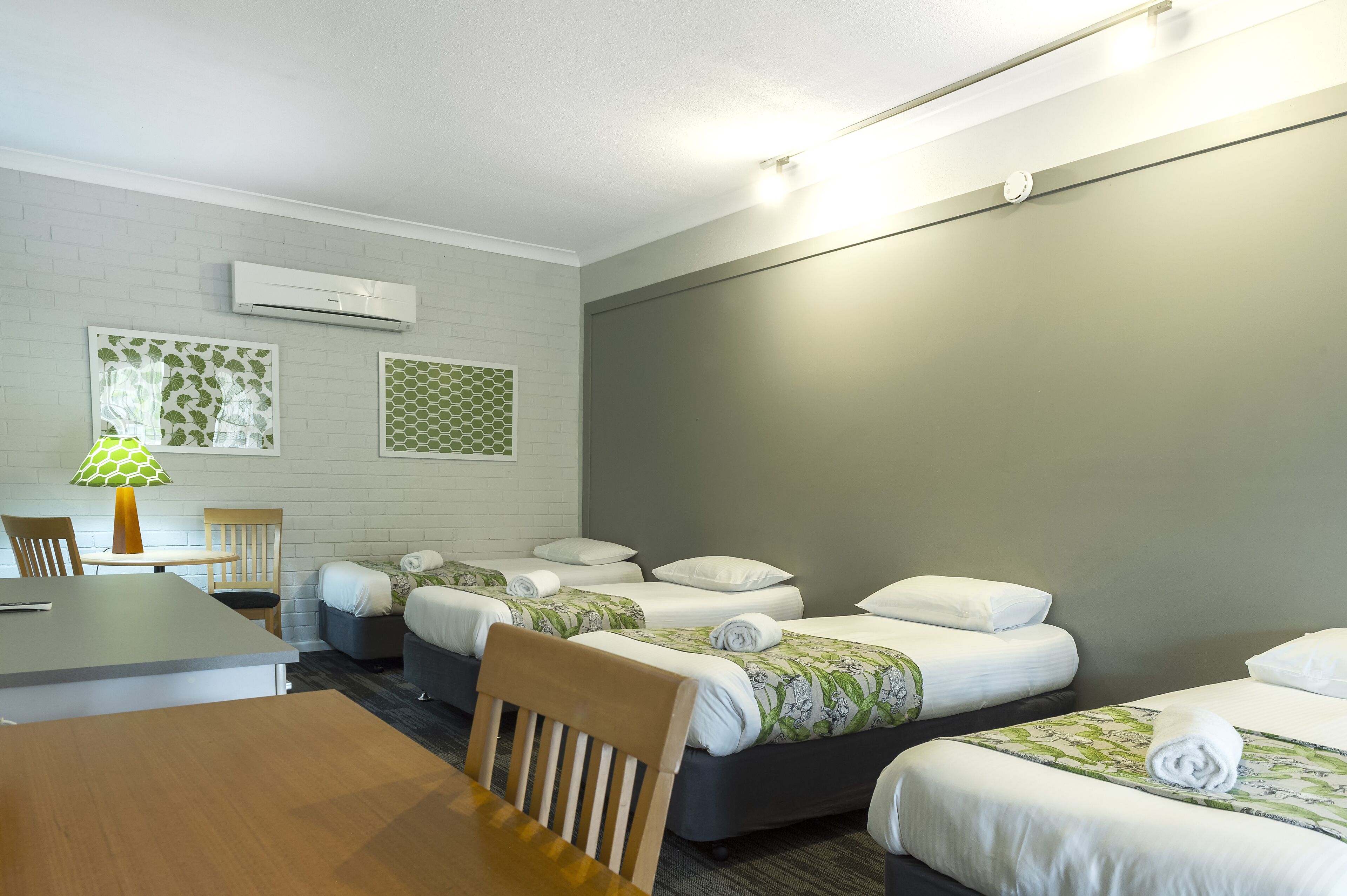 A hotel room with two beds, a desk, and a chair.