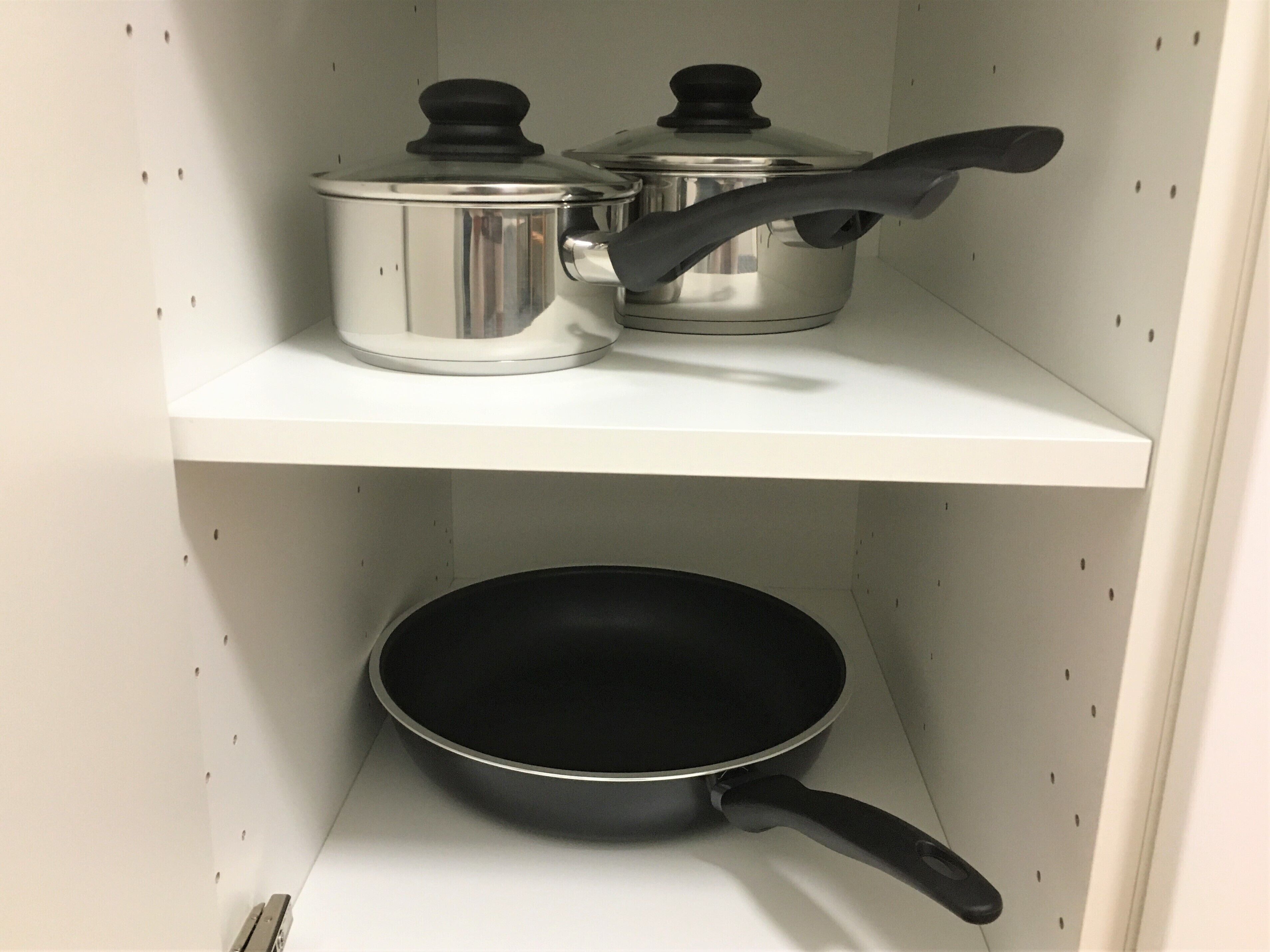 Une étagère de cuisine avec une casserole et une poêle en acier inoxydable.